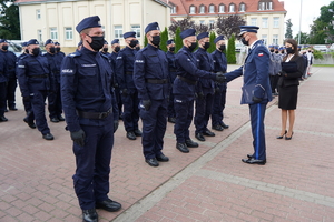 Komendant Wojewódzki gratuluje i przekazuje teczkę policjantowi