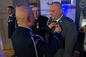 policjant przypina do munduru funkcjonariusza medal