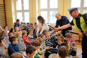 redaktor gazety, komendant Policji i policjant rd rozdają odblaski