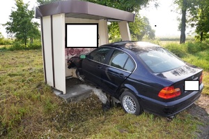 Wiata przystanku PKS. Przednimi kołami stoi w niej granatowy samochód marki BMW