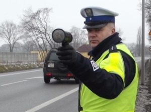 policjant ruchu drogowego stoi na drodze z miernikiem prędkości