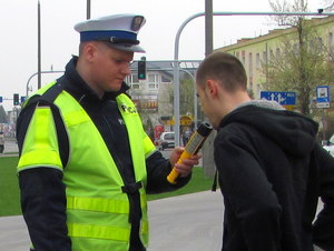 policjant na drodze prowadzi badanie trzeźwości młodego mężczyzny