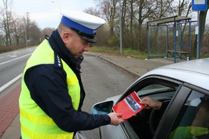 policjant przekazuje kierującemu opaskę odblaskową i ulotkę