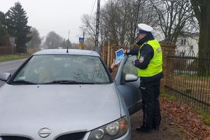 policjant wręcza kierowcy ulotkę