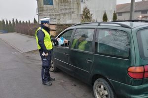 policjant wręcza kierowcy ulotkę