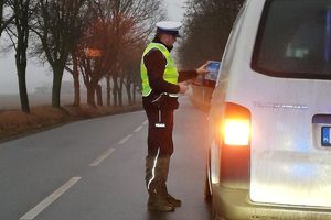 policjant wręcza kierowcy ulotkę