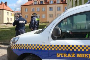 policjant i strażnik przy pojeździe straży miejskiej