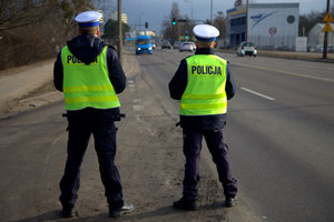 dwóch policjantów ruchu drogowego stojących tyłem przy drodze