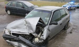 opel po kolizji,w tle drugie auto i radiowóz