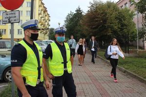 policjanci przy szkole, w tle idą uczniowie