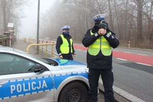 policjanci przy radiowozie - jeden z miernikiem prędkości