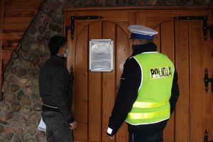 policjant z pracownikiem sanepidu przed wejściem do hotelu