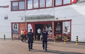 policjanci przed halą sprzedażową sklepu