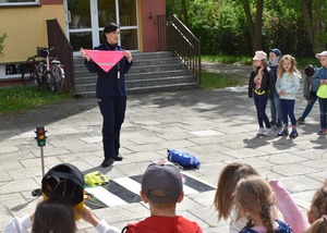 policjantka pokazuje dzieciom chustę z paskiem odblaskowym