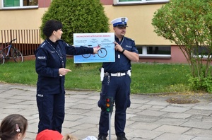 dwóch policjantów pokazuje plakat przedstawiający rower i jego wyposażenie