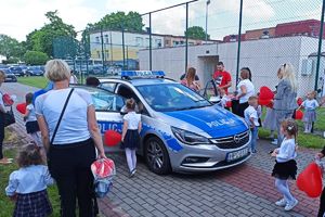 dzieci z rodzicami oglądają policyjne wyposażenie na przyszkolnym pikniku