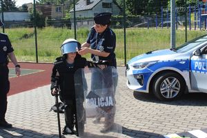 policjantka pomaga chłopcu przymierzyć strój szturmowy