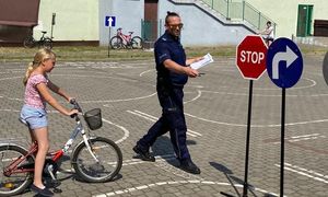 policjant, obok dziewczynka na rowerze