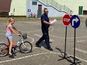 policjant, obok dziewczynka na rowerze