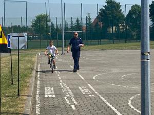 policjant kontroluje prawidłowy przejazd chłopca