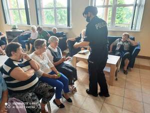 policjantka rozdaje seniorom ulotki i notesy