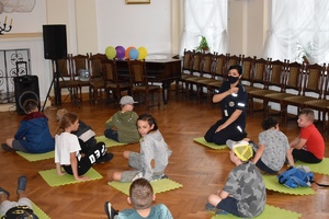 profilaktyk policyjny siedzi na podłodze z dziećmi w sali Miejskiego Centrum Kultury w Lipnie