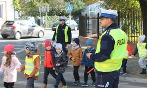 policjant na przejściu dla pieszych przeprowadza dzieci przez jezdnię