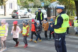 policjant na przejściu dla pieszych przeprowadza dzieci przez jezdnię