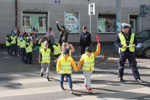 policjant na przejściu dla pieszych przeprowadza dzieci przez jezdnię