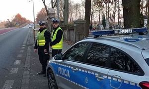 policjanci przy radiowozie w tle cmentarz