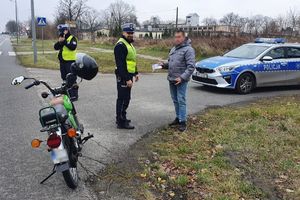 policjant wręcza kierowcy ulotkę, drugi mierzy predkość