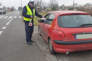 policjant wręcza kierowcy ulotkę