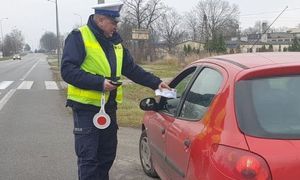 policjant wręcza kierowcy ulotkę