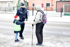 chłopiec z policjantką wręcza  odblask przechodniowi