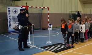 policjant uczy dzieci przechodzić przez jezdnię