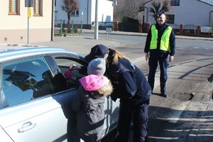 policjantka z dzieckiem rozmawiają z kierowcą, w tle uśmiechnięty policjant