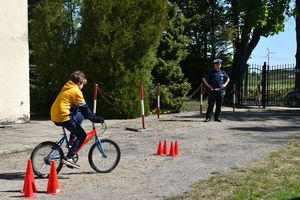 chłopiec pokonuje slalom na rowerze, policjant patrzy