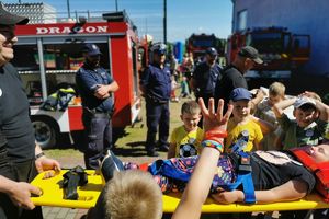 dzieci zgromadzone przy strażakach, dziewczynka na desce ratowniczej
