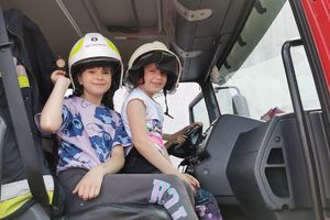 dziewczynki w strażackich hełmach w pojeździe gasniczym
