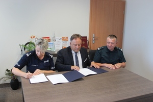 za stołem komendant, starosta i inspektor podpisują tekst porozumienia