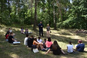 Policjant wraz z pracownikiem sanepidu rozmawia z harcerzami na temat bezpieczeństwa.