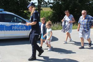 policjantka prowadzi dzieci z dziadkami na miejsce akcji profilaktycznej