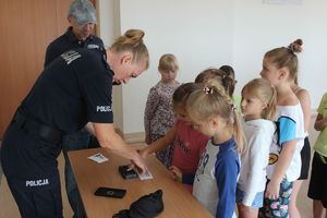 policjantka pomaga dzieciom zrobić odbitki linii papilarnych