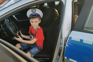 chłopiec w policyjnym radiowozie w czapce policjanta drogówki