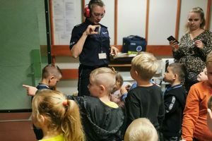 policjantka w ochraniaczach wzroku i słuchu rozmawia z dziećmi na strzelnicy