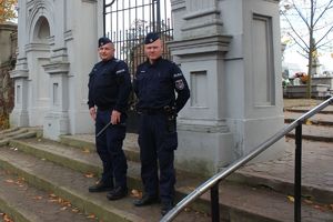 policjanci przed bramą cmentarza