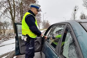 policjant wręcza kierowcy ulotkę i odblask