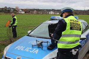 policjant przy radiowozie, na masce pojazdu dron