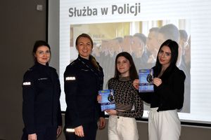 policjantki z uczennicami trzymającymi plakaty promujące zawód policjanta