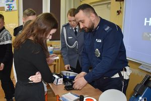 policjant pokazuje uczniom wyposażenie do służby